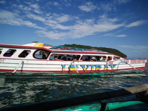 a white boat with people on it in the water at Alona's Traditional Filipino Home near 100 Islands Wharf in Alaminos