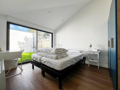 Un dormitorio con una cama y una ventana grande. en Vincent, en Stella-Plage