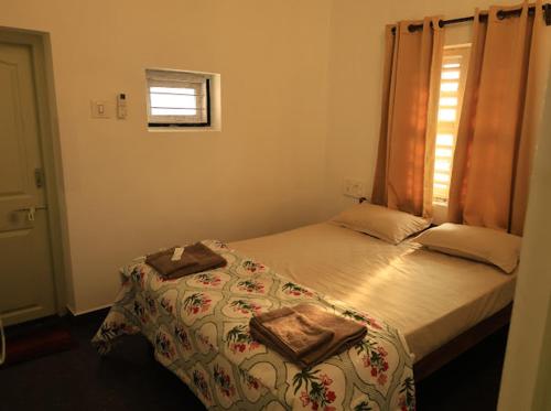 a small bedroom with a bed and a window at Mannath lands end Beach house in Kaup