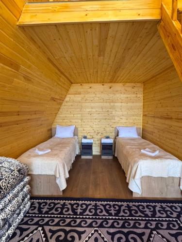 a room with two beds in a wooden room at Son-Kul A-Frame & Yurt Camp in Song-Kul