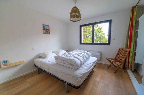 Una habitación con una cama con sábanas blancas. en Valentin, en Stella-Plage