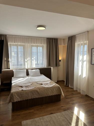 a bedroom with a large bed and windows at Къща за гости Девина in Devin