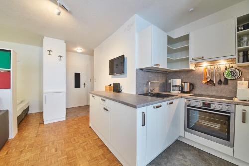 eine Küche mit weißen Schränken und einem Herd in der Unterkunft Appartement Relax & Sport in Saalbach-Hinterglemm