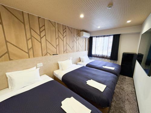 a hotel room with two beds and a tv at Hotel Livemax Budget Kagoshima Tenmonkan in Kagoshima