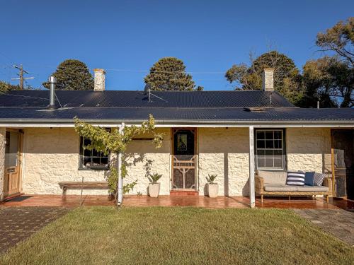 a white brick house with a bench on a patio at Clonmara Country House and Cottages in Port Fairy