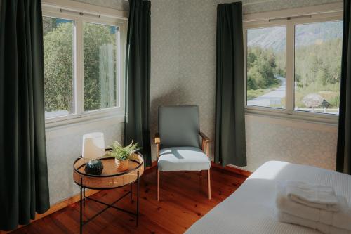 a bedroom with a chair and a table and windows at Villa Fjellheim in Luster