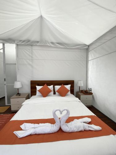 two swans are laying on a bed in a tent at Ohara Glamping in Kubupenlokan