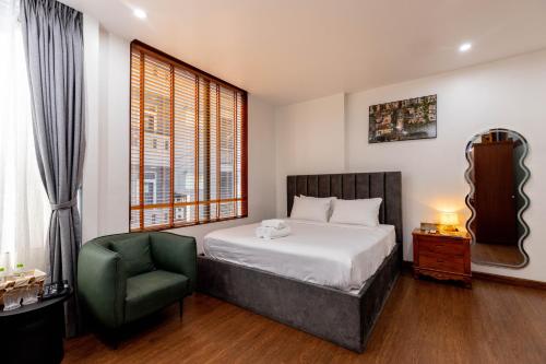 a bedroom with a bed and a chair and a window at Sài Gòn Heat Hotel in Ho Chi Minh City