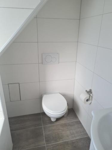 a white bathroom with a toilet and a sink at Monstera Apartment in Groß-Umstadt