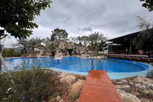 a large swimming pool in a resort with a waterfall at Honey Queen Resort in Ban Tha Manao