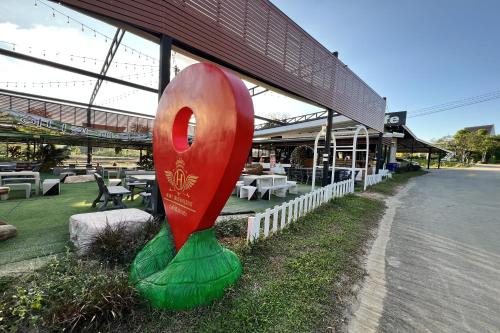 a large red and green sculpture in front of a building at Honey Queen Resort in Ban Tha Manao