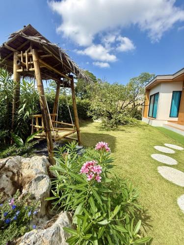 a small hut in a yard with flowers at Ao Nang Escapes Tropical Villas & Studios in Ao Nang Beach