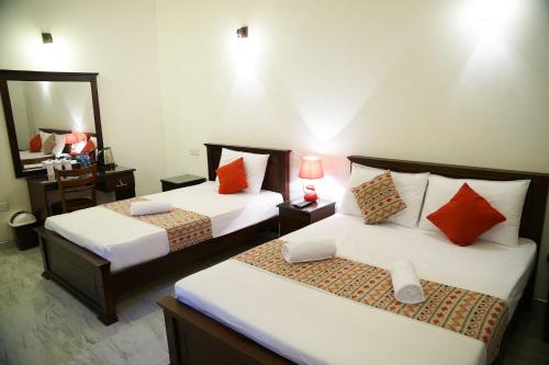a hotel room with two beds and a mirror at Kandy Moon Hills Hotel in Kandy