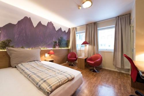 um quarto de hotel com uma cama, uma secretária e cadeiras em Senja Hotell em Finnsnes