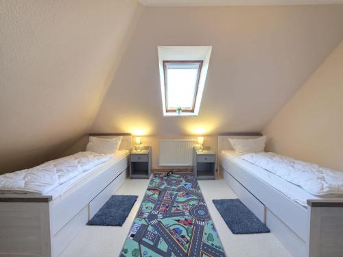 a attic room with two beds and a window at Ferienwohnung Strandbrise in Dornum