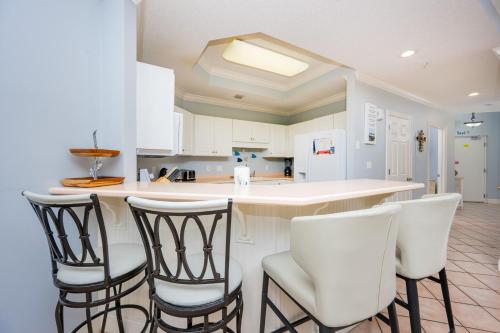 a kitchen with white cabinets and bar stools at Phoenix on the Bay 1122 condo in Orange Beach