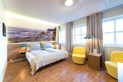 um quarto com uma cama grande e uma cadeira amarela em Senja Hotell em Finnsnes