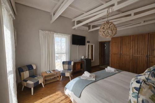 a bedroom with a bed and two chairs and a television at Haus Müller in Clanwilliam