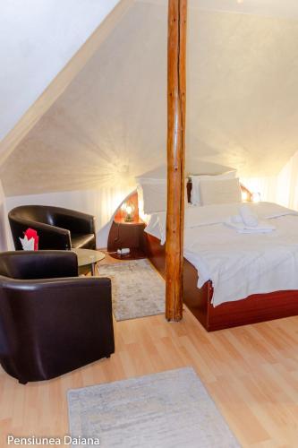 a bedroom with a bed and two chairs in a room at Vila Daiana- Acceptam vouchere vacanta in Moieciu de Jos