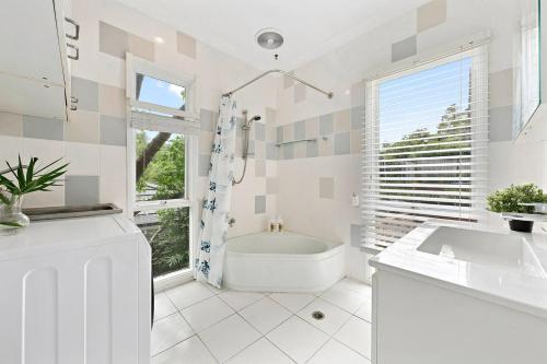 a white bathroom with a tub and a sink at Elegant 4BR Sanctuary with Private Pool in Warrawee