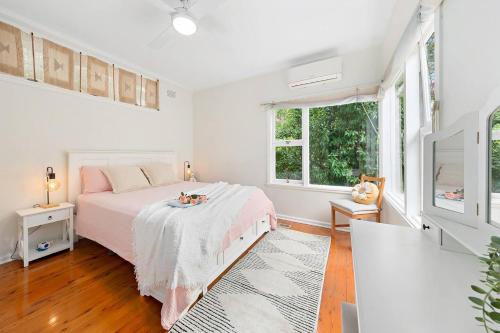 a white bedroom with a bed and two windows at Elegant 4BR Sanctuary with Private Pool in Warrawee