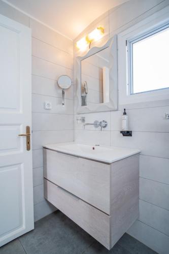 a white bathroom with a sink and a mirror at Salvatore Caldera Suites in Imerovigli