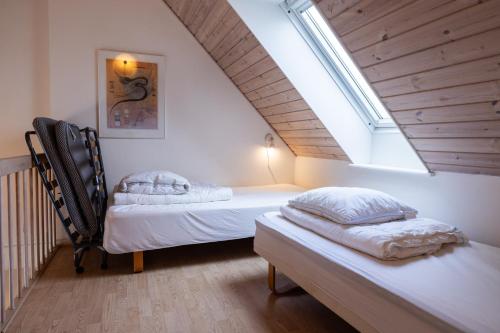 two beds in a attic room with a window at Skagen Strand Holiday Center in Hulsig