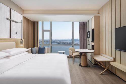 a hotel room with a bed and a tv and a table at Qingdao Marriott Hotel Jiaozhou in Qingdao
