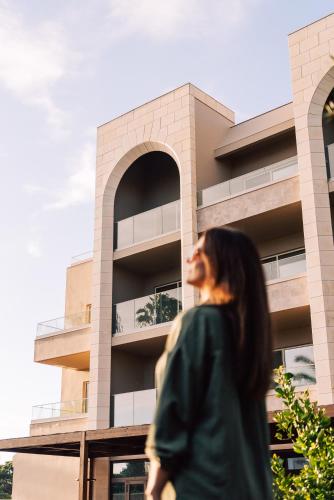 a woman walking in front of a building at Falésia Hotel - Adults Only in Albufeira