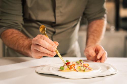 a man holding a spoon and a plate of food at Falésia Hotel - Adults Only in Albufeira