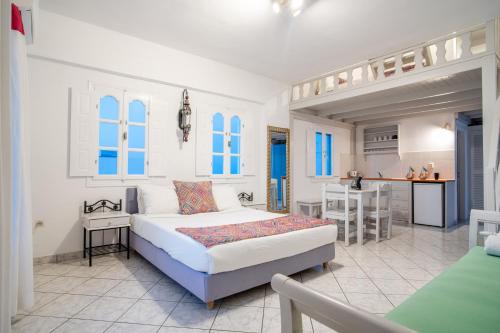 a white bedroom with a bed and a kitchen at Salvatore Caldera Suites in Imerovigli