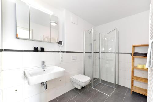 a white bathroom with a sink and a toilet at Ferienwohnung Oberdeck in Juliusruh