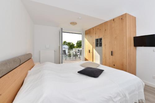 1 dormitorio con cama blanca y pared de madera en Ferienwohnung Oberdeck, en Juliusruh