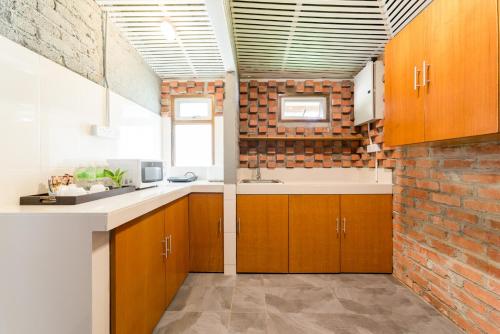 a kitchen with wooden cabinets and a brick wall at The Ocean Residence Langkawi in Kuah