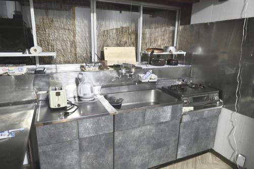 a stainless steel kitchen with a sink and a stove at 釣り宿yasakabase guesthouse in Sado