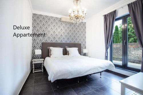 a bedroom with a white bed and a chandelier at Apartlogie in Tongeren