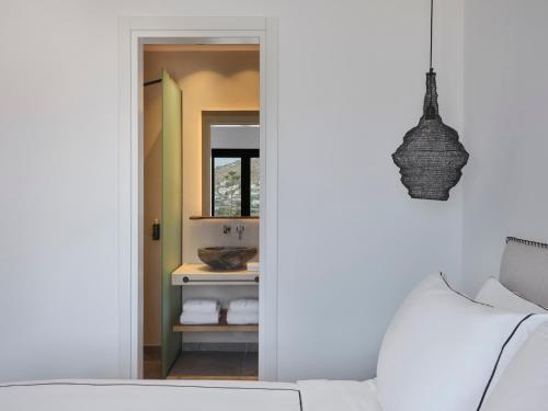 a bathroom with a mirror and a white couch at Kalea Mykonos in Ornos