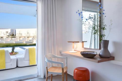 a room with a table and a chair and a window at Myconian Korali Relais & Chateaux in Mýkonos City