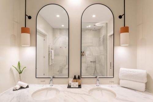two sinks in a bathroom with two mirrors at Parador de Ibiza in Ibiza Town