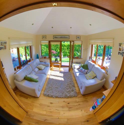 an open living room with white couches and a rug at Ty Melin in Pembroke Dock