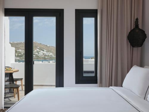 a bedroom with a large white bed and windows at Kalea Mykonos in Ornos