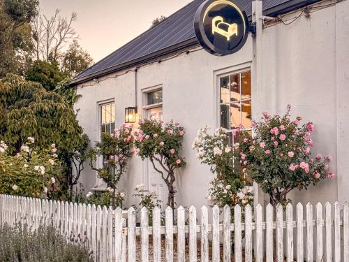 a white house with a white fence and flowers at Clonmara Country House and Cottages in Port Fairy