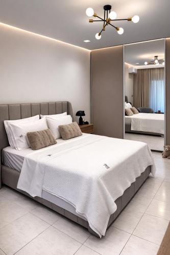 ein Schlafzimmer mit einem großen weißen Bett und einem Spiegel in der Unterkunft TReverie Stay -Modern 3BR Apartment for Families & Friends in Thessaloniki
