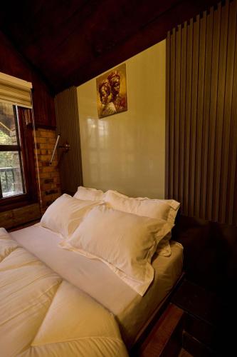 een bed met witte lakens en kussens in een slaapkamer bij Premier Cabins in North Legon