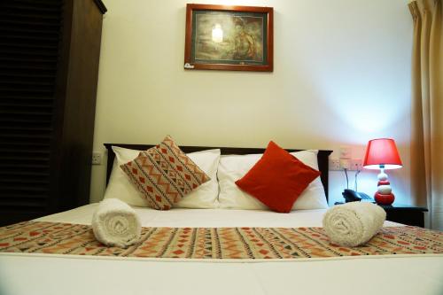 a bed with pillows and a picture on the wall at Kandy Moon Hills Hotel in Kandy