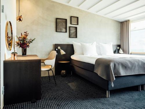 a bedroom with a bed and a desk and a chair at Hotel Føroyar in Tórshavn
