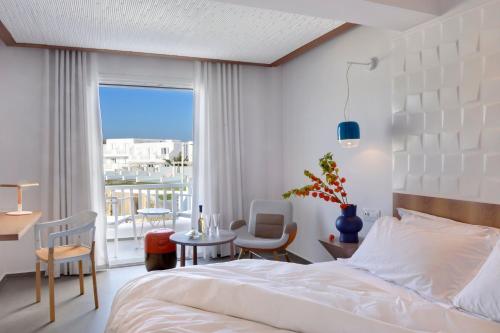 a bedroom with a bed and a table and chairs at Myconian Korali Relais & Chateaux in Mýkonos City