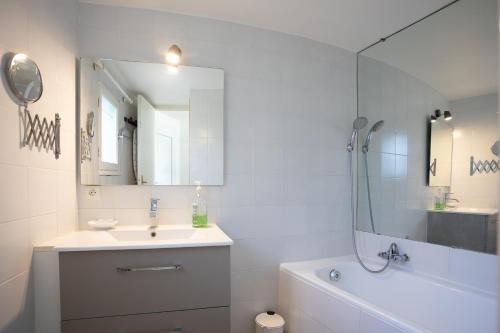 a white bathroom with a sink and a mirror at Meublé La Sergerie in Le Lavandou