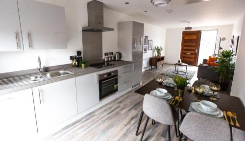 a kitchen with white cabinets and a table with chairs at The Interchange - 2-Bed - Brand New - Central in Manchester