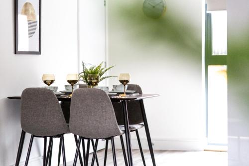 a dining room table with three chairs and wine glasses at The Interchange - 2-Bed - Brand New - Central in Manchester